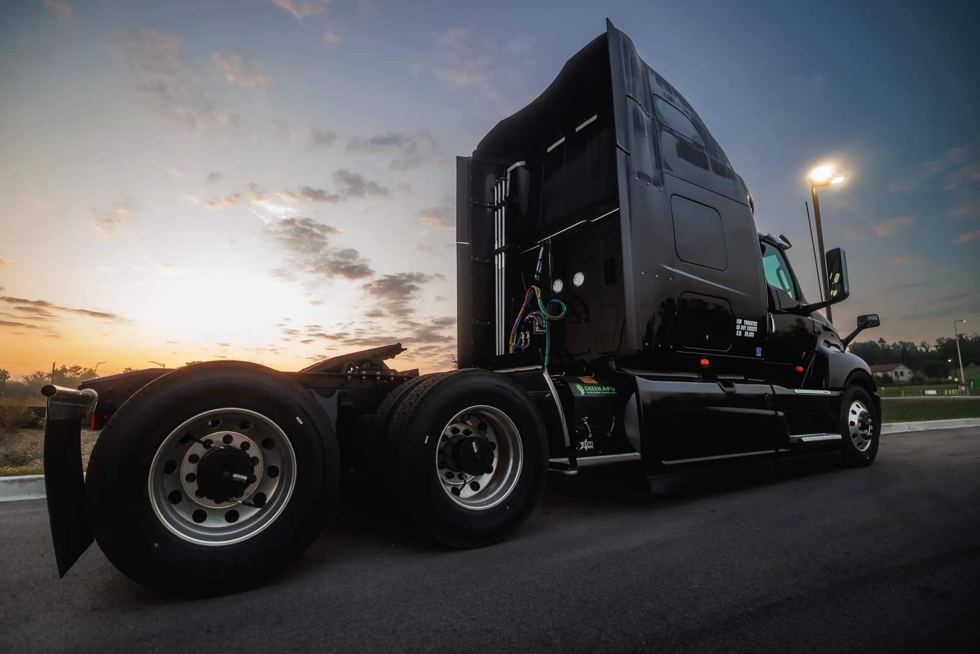 A semi-truck at dusk with a Green APU auxiliary power unit mounted on the frame rail